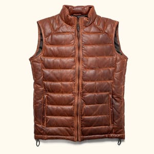 May include: A brown leather puffer vest with a zip closure. The vest has a quilted design and a stand-up collar.