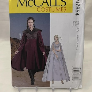 May include: McCall's Costumes pattern M7854. The package features illustrations of two costume designs: a burgundy medieval-style gown with a cape and a light blue gown with a cape. The package has a yellow top with the brand name and a white background.