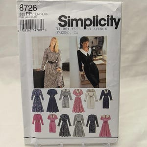May include: A Simplicity sewing pattern packet, featuring images of dresses. The packet is white with the number 8726 at the top. The text "Simplicity" is printed in black. The packet includes size information and a barcode.