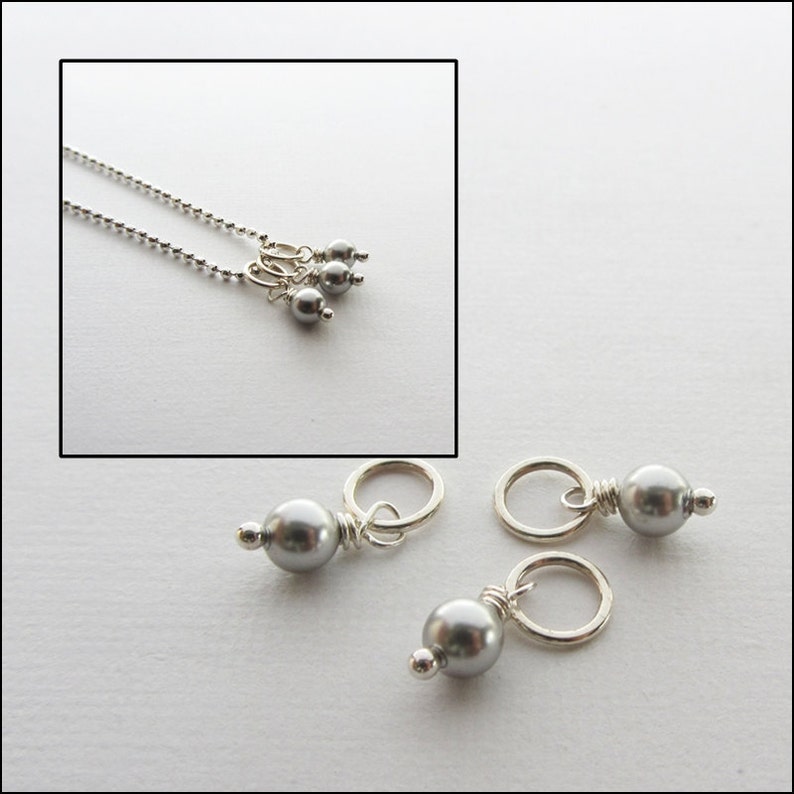 May include: Three silver charms with a gray pearl on each. The charms have a small loop at the top for attaching to a necklace or bracelet.