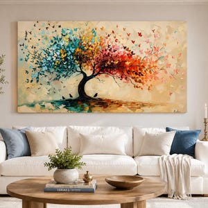 May include: A large rectangular canvas painting featuring a central tree with a thick dark trunk. The foliage transitions from vibrant blue and teal on the left to warm orange, red, and yellow on the right, with many small butterfly shapes.
