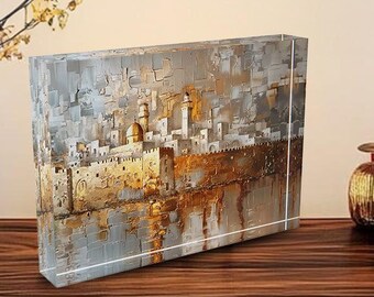 May include: A glass block with a painting of a city skyline with gold and gray tones. The city is reflected in the water below.