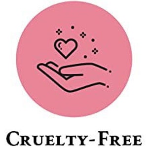 Puede incluir: Un c&iacute;rculo rosa con un contorno negro contiene un dibujo de l&iacute;nea negra de una mano sosteniendo un coraz&oacute;n con destellos. El texto "CRUELTY-FREE" est&aacute; debajo del c&iacute;rculo.