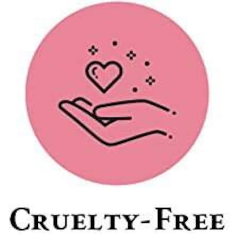 May include: A pink circle with a black outline contains a black line drawing of a hand holding a heart with sparkles. The text "CRUELTY-FREE" is below the circle.