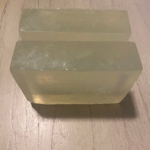 May include: Two clear rectangular bars of soap, stacked on top of each other. The soap is translucent and has a slightly frosted appearance.