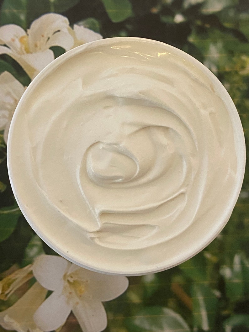 May include: A white, creamy, swirl-like texture in a white container. The container is on a green and white floral background.