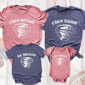 May include: A set of four t-shirts featuring a tornado design with the text "Storm Watcher", "Storm Chaser", "Big Tornado", and "Tiny Tornado". The shirts are in various shades of pink and blue.