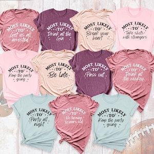 May include: Nine different t-shirts with the text "Most Likely To" followed by a funny phrase. The shirts are in various colors, including pink, blue, purple, and beige.