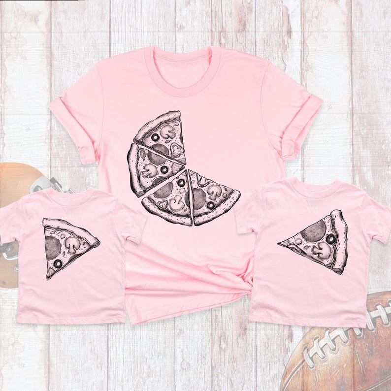 May include: Two pink t-shirts with a pizza slice graphic. The larger shirt has a graphic of three pizza slices, while the smaller shirt has a graphic of one pizza slice.