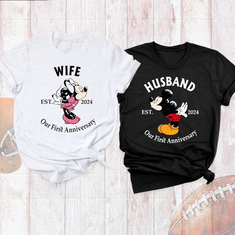 Puede incluir: Dos camisetas blancas con texto negro e im&aacute;genes. La primera camiseta dice "Wife Est. 2024 Our First Anniversary" y presenta una imagen de dibujos animados de Minnie Mouse besando a Mickey Mouse. La segunda camiseta dice "Husband Est. 2024 Our First Anniversary" y presenta una imagen de dibujos animados de Mickey Mouse besando a Minnie Mouse.