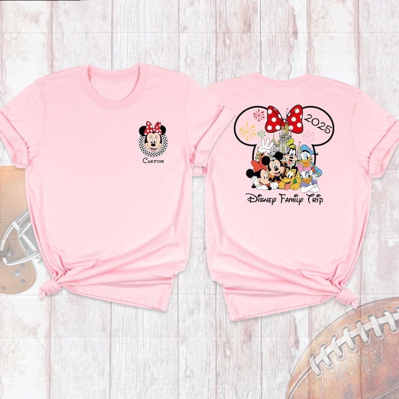 Puede incluir: Dos camisetas de color rosa claro. Una presenta un gr&aacute;fico de Minnie Mouse con la palabra "Custom" debajo. La otra camiseta tiene un dise&ntilde;o de oreja de Mickey Mouse con "2025" y un grupo de personajes de Disney, con las palabras "Disney Family Trip".