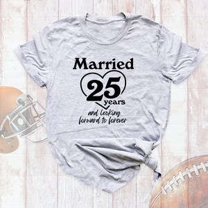 May include: A gray t-shirt with the text "Married 25 years and looking forward to forever" printed in black. The text is inside a heart shape.