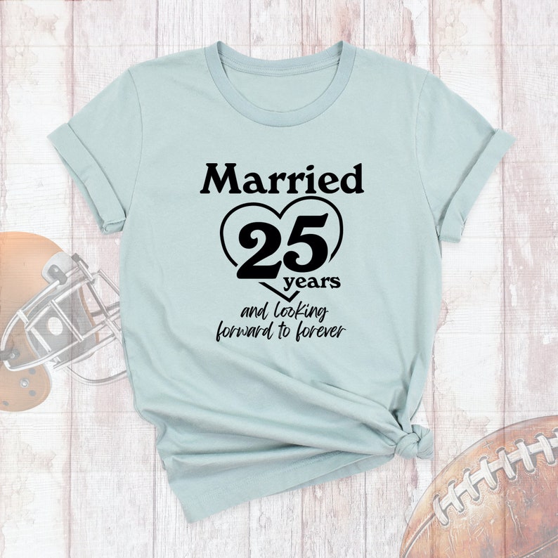 May include: A light blue t-shirt with black text that reads "Married 25 years and looking forward to forever". The text is in a heart shape.