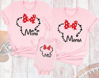 May include: Two light pink short-sleeve t-shirts and one light pink short-sleeve baby bodysuit. Each garment features a red and white polka dot bow above a heart shape formed by small black mouse silhouettes. The shirts say Mimi and Mama.