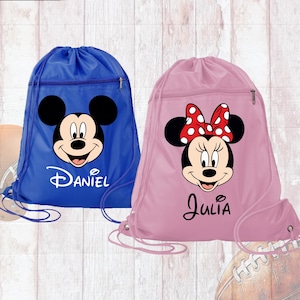 May include: Two blue and pink drawstring bags with Mickey Mouse and Minnie Mouse faces printed on them. The bags have the names "Daniel" and "Julia" printed on them.