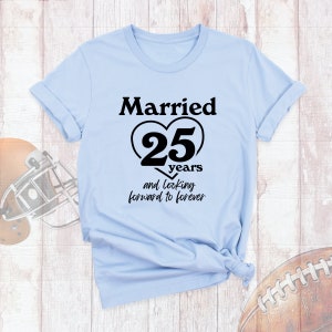 May include: Light blue t-shirt with black text that reads "Married 25 years and looking forward to forever". The number 25 is inside a black heart.