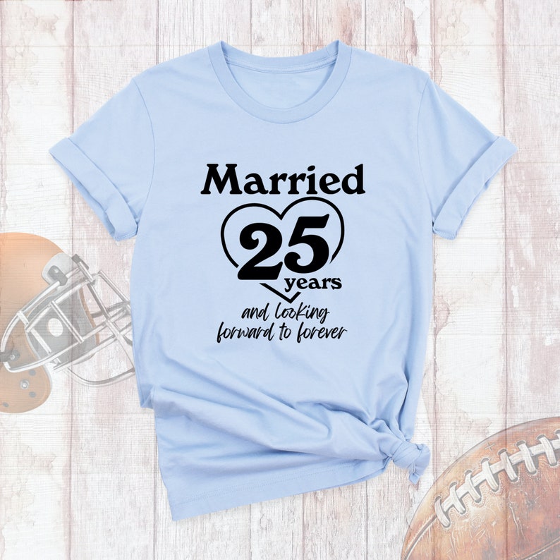 May include: Light blue t-shirt with black text that reads "Married 25 years and looking forward to forever". The number 25 is inside a black heart.