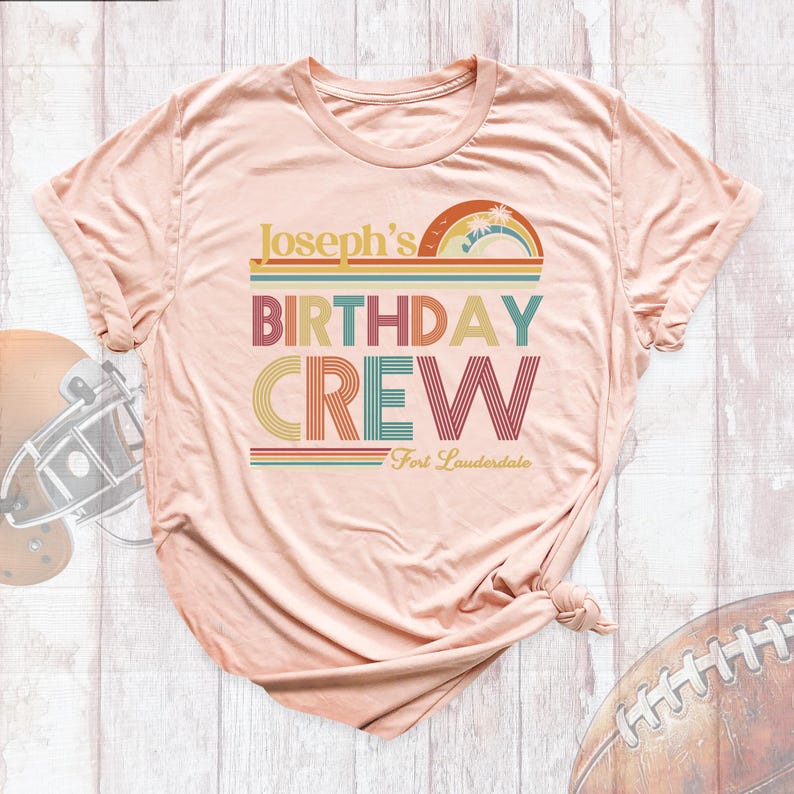 May include: A peach-colored t-shirt with a retro-style graphic that says "Joseph's Birthday Crew" with a rainbow and palm tree design. The text "Fort Lauderdale" is printed below the graphic.