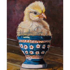May include: A yellow chick sits inside a blue and white egg cup with a floral pattern. The chick is looking to the right and has its head tilted. The background is a dark brown color.