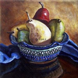 May include: A blue and white ceramic bowl filled with four pears. The pears are red, green, and yellow. The bowl is sitting on a blue cloth.