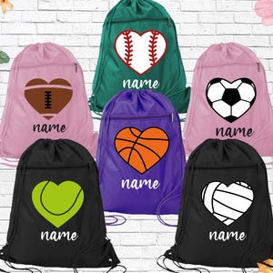May include: A collection of drawstring sports bags in various colors, each featuring a heart-shaped graphic of a different sport: baseball, football, basketball, soccer, tennis, and volleyball. Each bag has the word "name" printed below the graphic.