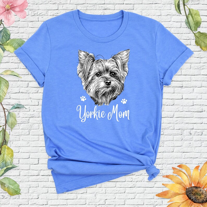 May include: A light blue t-shirt with a black and white illustration of a Yorkshire Terrier and the text "Yorkie Mom".