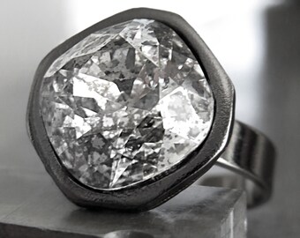 May include: A silver ring with a large, clear, faceted gemstone set in a bezel setting.