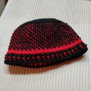 May include: A black and red knitted beanie hat with a textured pattern.