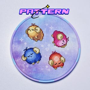 May include: A cross-stitch pattern in a round hoop featuring four cartoon sheep in shades of brown, pink, blue, and red. The background is a watercolor wash of purple and blue. The word "PATTERN" is at the top.