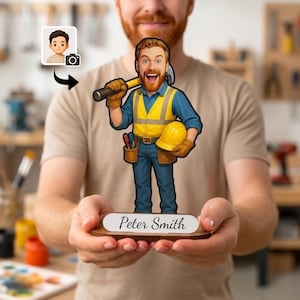 Op de afbeelding: Een gepersonaliseerd houten karikatuurbeeldje van een bouwvakker met baard, gekleed in een blauw overhemd, geel veiligheidsvest en bruine handschoenen, met een hamer en veiligheidshelm. De voet toont de naam Peter Smith in zwarte letters.
