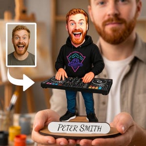 Puede incluir: Una figura personalizada de cabeza oscilante de una persona con barba roja que viste una sudadera negra con un gráfico de neón, de pie detrás de un controlador de DJ. La figura está sobre una base de madera con una placa blanca Peter Smith.
