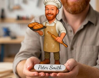 May include: A wooden cutout figure of a smiling baker wearing a white chef hat, a tan apron, and light-colored shirt. The baker holds a tray with two loaves of bread and a rolling pin. A white base features the printed text Peter Smith.