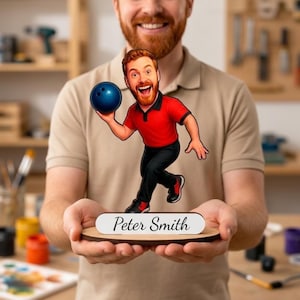 May include: A custom acrylic tabletop display featuring a cartoon illustration of a red-haired person in a red polo shirt and black pants holding a blue bowling ball. The figure stands on a wooden base with a white plaque reading Peter Smith.
