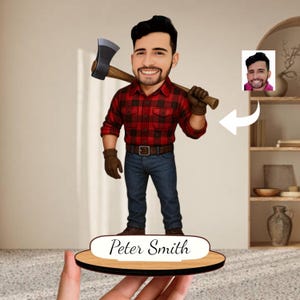 Könnte beinhalten: Holzfigur eines Mannes in einem rot karierten Hemd und blauen Jeans, der eine Axt hält. Die Figur hat ein cartoonartiges Design und ist auf einem Holzsockel mit dem Namen "Peter Smith" in weißer Schrift montiert. Die Figur ist etwa 15 cm hoch.