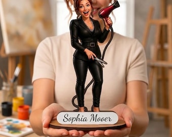 May include: A standing figurine of a person with auburn hair wearing a black blazer and black trousers. The figure holds a red hair dryer in one hand and silver scissors in the other. A white base features the name Sophia Moover in black script.