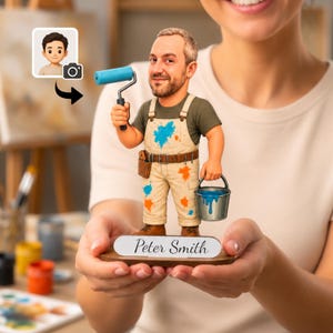 May include: A custom bobblehead figurine of a painter wearing beige overalls with blue and orange paint splatters over a green t-shirt. The figure holds a blue paint roller and a metal bucket of blue paint, standing on a base labeled Peter Smith.