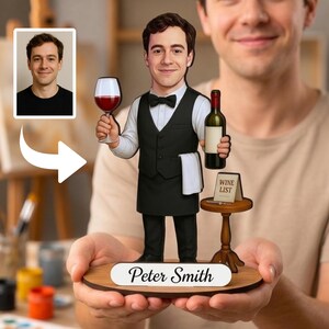 Op de afbeelding: Een gepersonaliseerd bobblehead-figuur van een ober in een wit overhemd, zwart vest en vlinderdas, met een wijnglas en een fles. Naast het figuur staat een tafeltje met een bordje met de tekst WINE LIST op een voetstuk met de naam Peter Smith.
