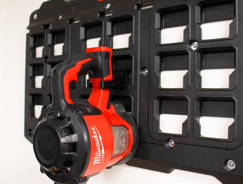 May include: A red and black Milwaukee power blower tool hanging on a black pegboard wall.