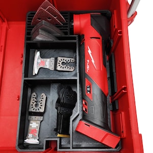 Puede incluir: Una multiherramienta roja y negra con varias cuchillas y almohadillas de lijado organizadas en una caja de herramientas roja. La multiherramienta está etiquetada como "FUEL" y "3.10 A". La caja tiene un inserto negro con compartimentos.