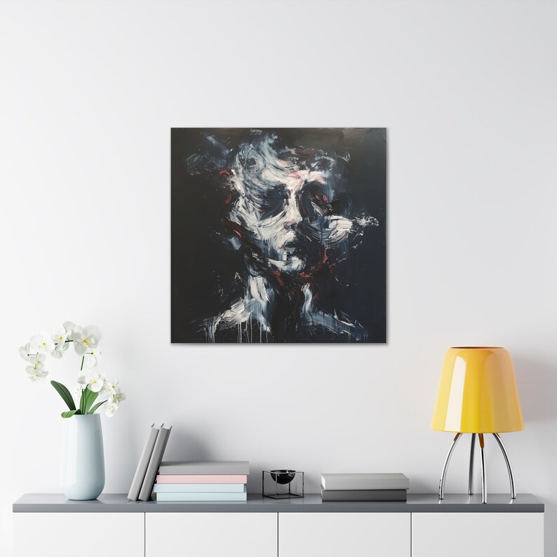 May include: Abstract portrait painting on canvas. The artwork features a face rendered in white, red, and gray brushstrokes against a black background. The painting is displayed on a white wall above a gray cabinet with decorative items.