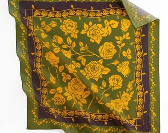 Könnte beinhalten: Quadratisches olivgrünes Tuch mit einem floralen Rosenmuster in Gelb und Dunkelviolett. Das Tuch hat einen Rand aus kleinen gelben Rosen und einen dunkelvioletten Innenrand. Das Tuch ist in der oberen rechten Ecke gefaltet.