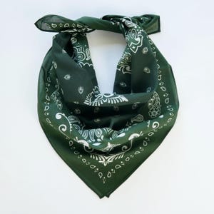 May include: A green bandana with a white paisley pattern. The bandana is folded into a triangle shape.