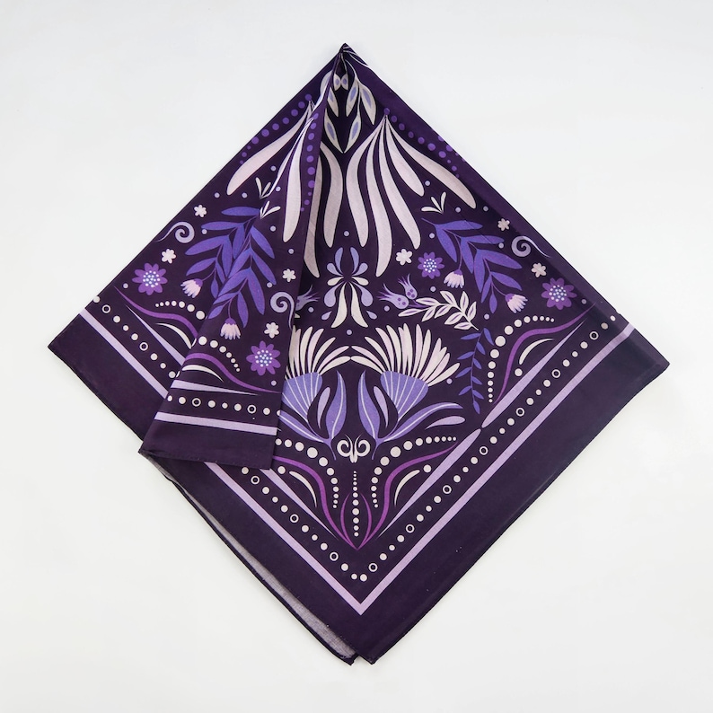 May include: A purple bandana with a floral pattern. The pattern features white and purple flowers, leaves, and swirls. The bandana has a dark purple background and a white border.