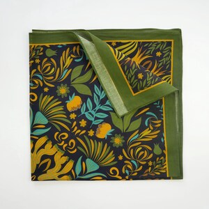 May include: A green and yellow floral patterned fabric square with a dark blue background. The fabric has a green border.