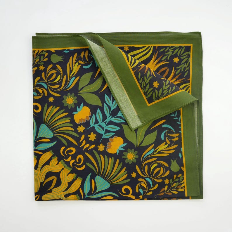 May include: A green and yellow floral patterned fabric square with a dark blue background. The fabric has a green border.