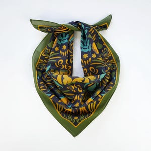 May include: A green and blue patterned bandana with a dark blue background and yellow floral designs. The bandana is folded into a triangle shape.