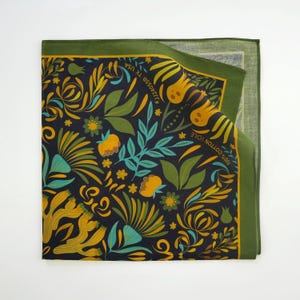 May include: A green and yellow floral patterned bandana with the text "100% COTTON VOILE" and "#JULIASSE TX USA" printed on it.