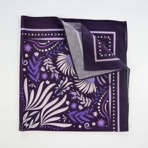 May include: Purple bandana with a floral pattern in shades of purple and white. The bandana has a white border with a repeating pattern of small circles.