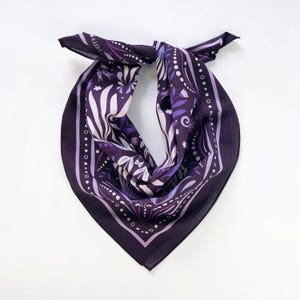 May include: A purple bandana with a floral pattern and white accents. The bandana has a white border with a repeating pattern of small circles.