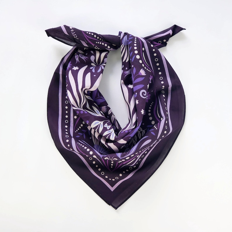May include: A purple bandana with a floral pattern and white accents. The bandana has a white border with a repeating pattern of small circles.